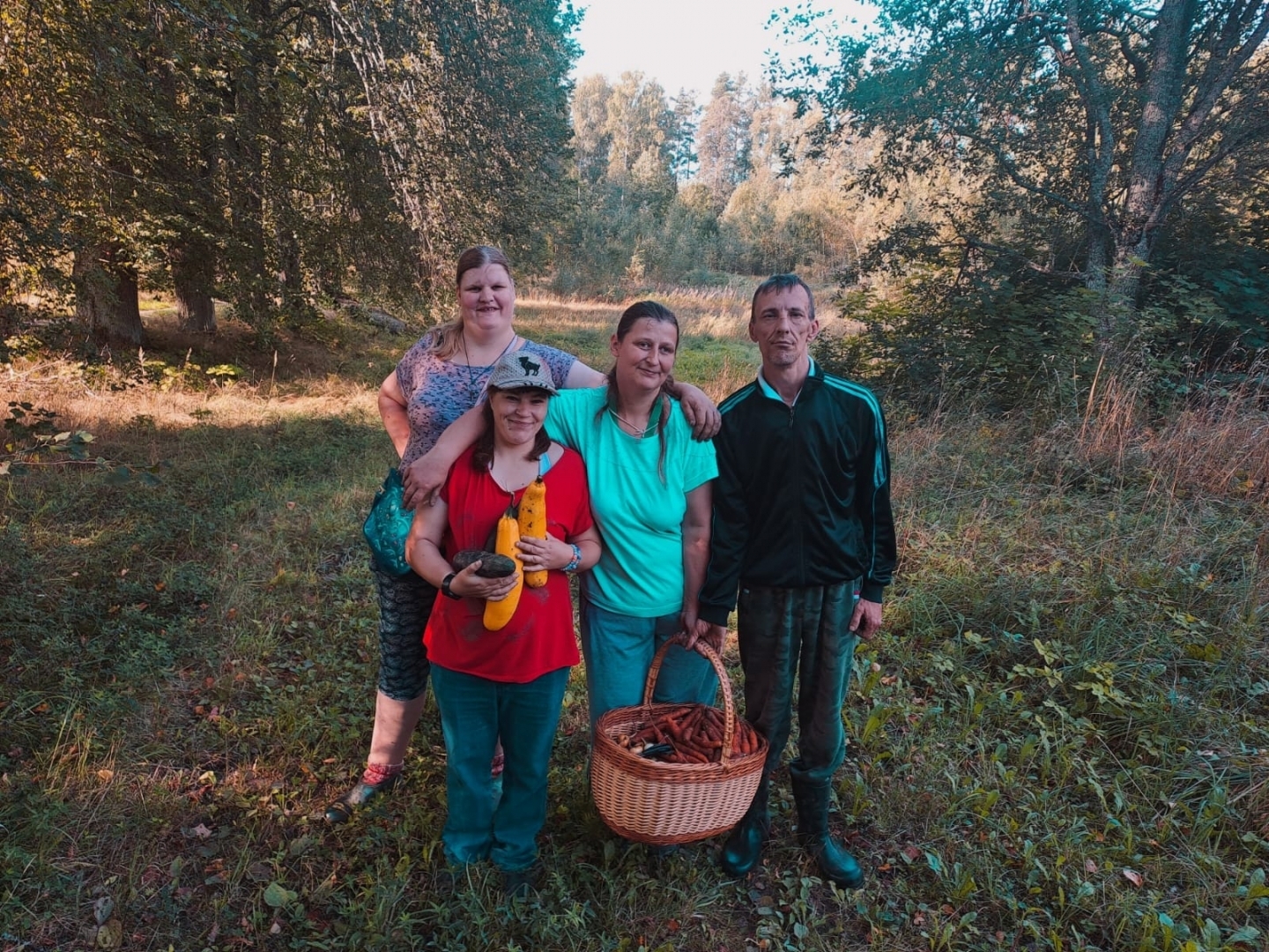 Cilvēku grupa stāv, rokās kabači, grozs ar dārzeņiem