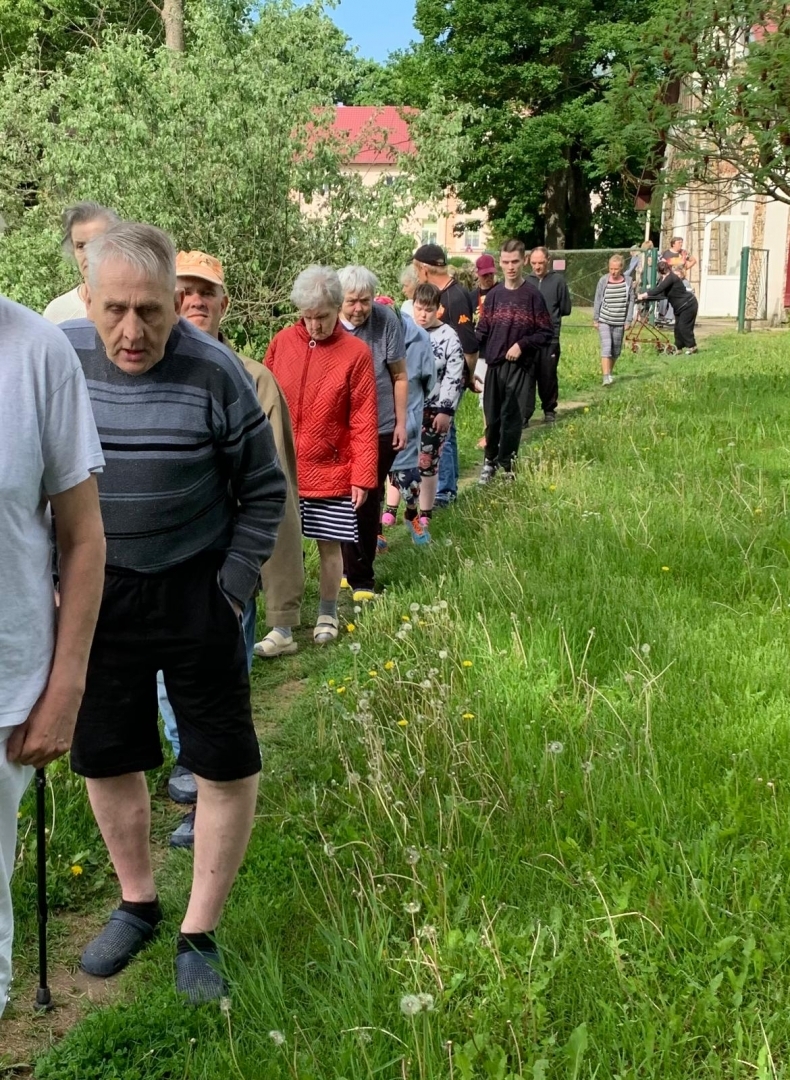 cilvēki pastaigā pa pļavu