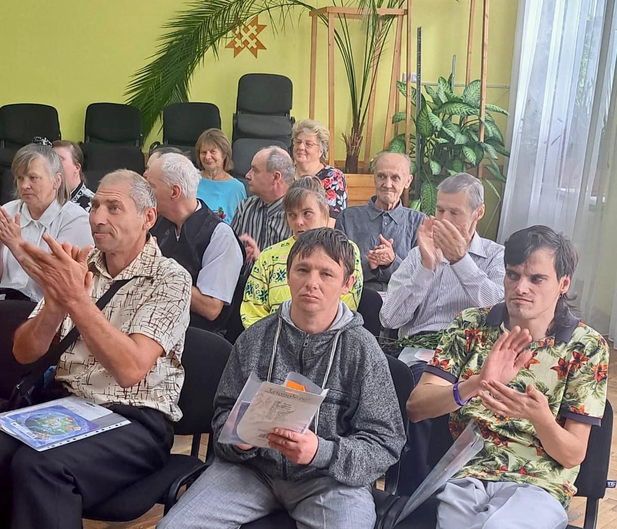 Cilvēki sēž aktu zālē, rokās dokumenti