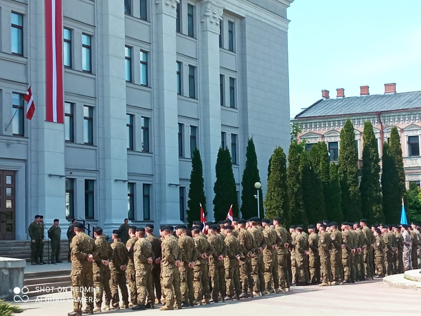 karāvīri stāv ierindā pie ēkas